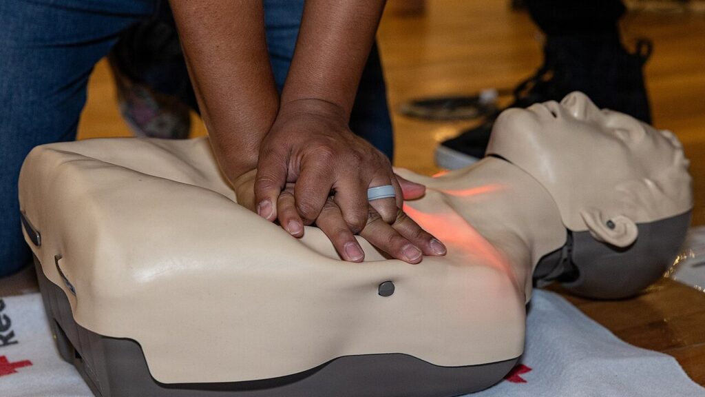 Hands performing chest compressions on a CPR training manikin